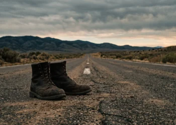 A lone man standing on a deserted highway at sunset.